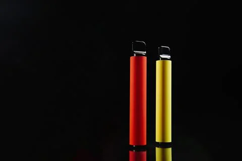Two disposable e-cigarettes on a dark background. Electronic vape, an 库存照片