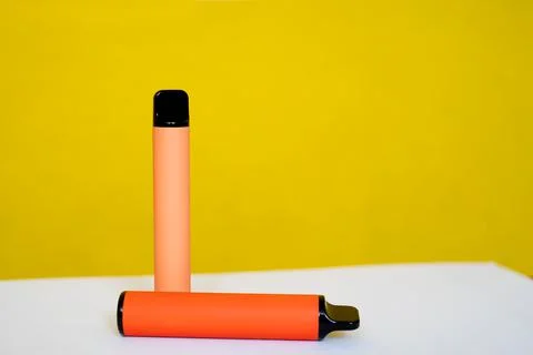 Two disposable e-cigarettes on a yellow background. The concept of modern smo Stock Photos