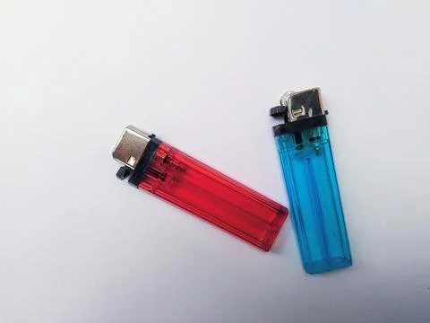 Two disposable lighters, one red and one blue, resting on a white surface. Fotos Stock