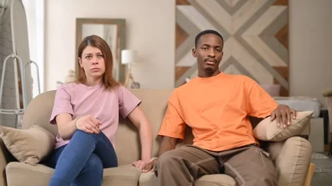 Two dissatisfied young people, a black guy and a white girl, look at the camera Stock Footage 287161285