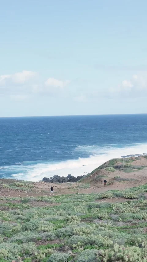 Two distant hikers walking along a scenic coastal trail Stock Footage 329865593
