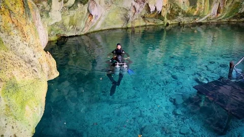 Two divers are preparing to dive into the cenote cave in Mexico. Blue lake su Stock Footage 90548596