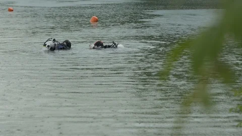 Two Divers Dive Under The Water. It's Raining. Stock Footage 127790693