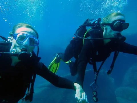 Two divers explore a thrilling underwater adventure in the clear blue ocean Stock Photos