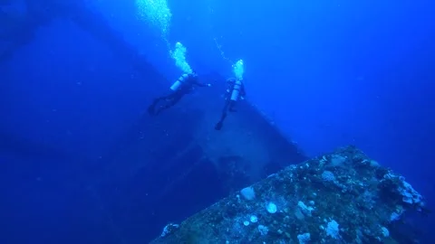 Two divers swim in front of the vast wreck of a ship. Stock Footage 325733459