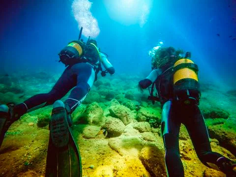 Two divers swimming away from camera. Stock Photos