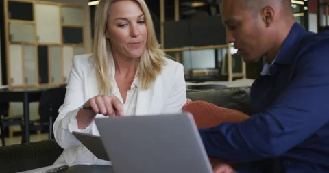 Two diverse business colleagues using laptop and discussing in a casual meeting Vídeos de archivo 146930697
