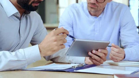 Two diverse business men analyzing financial data using digital tablet. Closeup Stock Footage 164101674