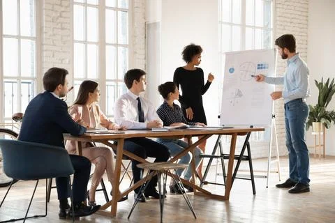 Two diverse business presenters explaining statistic data on whiteboard Stock Photos