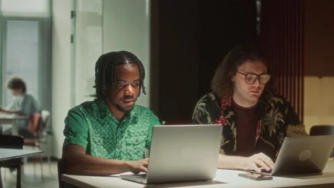 Two Diverse Colleagues Working Side by Side on Laptops at Office Desk Stock Footage 340496060