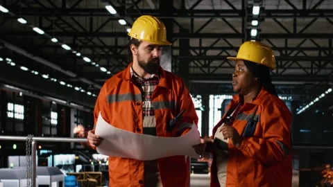 Two diverse engineers analyze blueprints and construction instructions Stock Footage 330088906