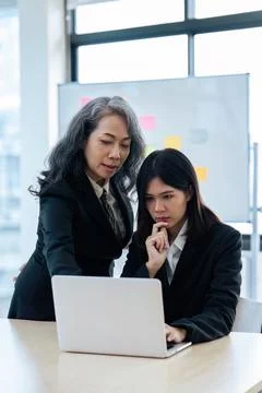 Two diverse financial assistant working on laptop while senior professional Stock Photos