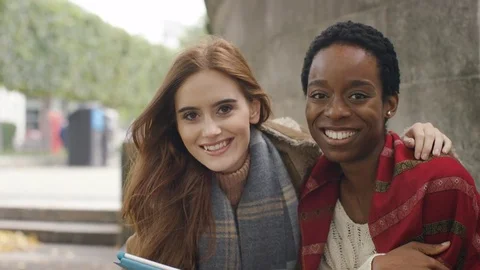 Two diverse friends using a digital tablet turn and smile to camera Stock Footage 80310721