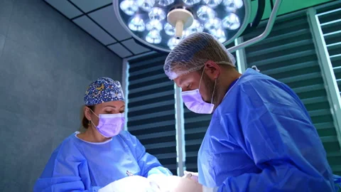 Two diverse medics cooperate at surgery on thyroid. Stock Footage 299690597