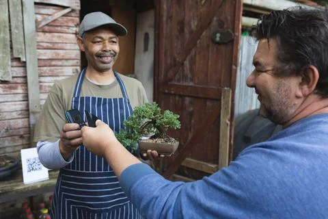 Two diverse men using contactless payments at garden centre Photos