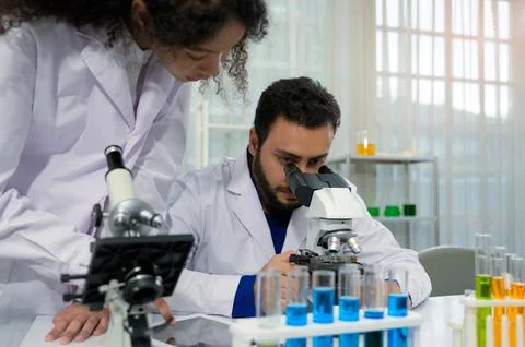 Two diverse scientists collaborating on microscope research Stock Photos