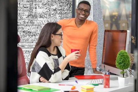 Two diverse work colleagues smiling and writing down notes while sitting Stock Photos