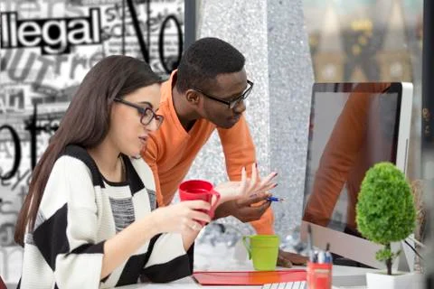 Two diverse work colleagues smiling and writing down notes while sitting Stock Photos