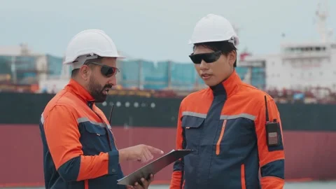 Two dock workers converse near a large vessel Vídeos de archivo 343333389