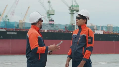 Two dock workers converse near a large vessel Stock Footage 343333401