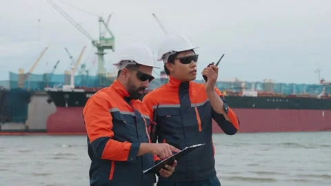 Two dock workers converse near a large vessel Stock Footage 343333513