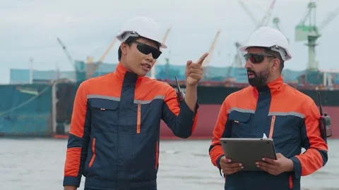 Two dock workers converse near a large vessel Stock Footage 343333716