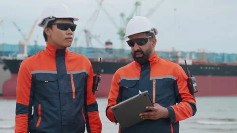 Two dock workers converse near a large vessel Stock Footage 343333717