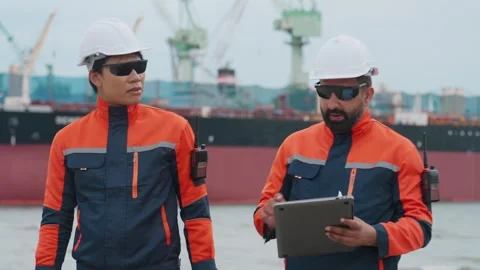 Two dock workers converse near a large vessel Stock Footage 343333748