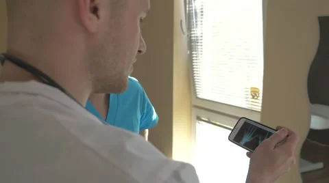Two doctors are looking at their patient x-ray on the mobile phone. Stock Footage 62949074