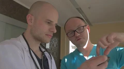 Two doctors are looking at their patient x-ray on the mobile phone. Stock Footage 62949255