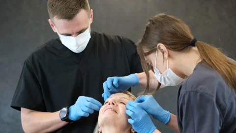 Two doctors are preparing an elderly woman for plastic surgery. Modern plastic Stock Footage 222791395