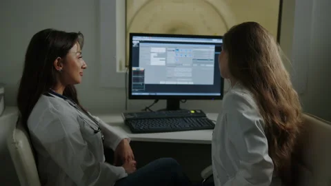 Two doctors are sitting in front of a computer in an X-ray cabinet Stock Footage 230243964