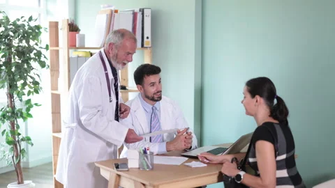 Two doctors are talking with a female patient at a clinic. Discussing treatment Stock Footage 341383919