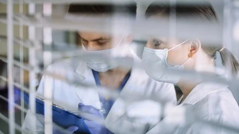 Two doctors behind window blinds. Stock Footage 128037816