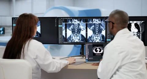 Two Doctors Carefully Examine X-ray Images On A Computer Screen, Discussing T Stock Photos