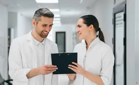 Two doctors with clipboard communicate standing at hospital corridor. Docto.. 写真素材