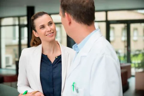 Two doctors discussing at hospital reception area Stock Photos