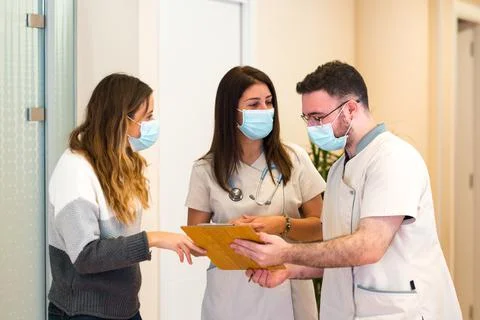 Two doctors discussing notes on clipboard together with female patient in Stock Photos