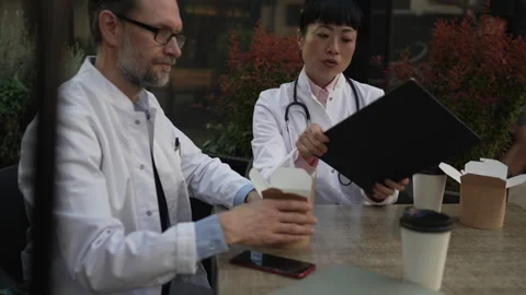 Two doctors discussing patient case during lunch break Video stock 333325471