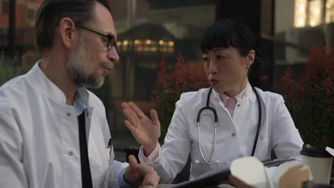 Two doctors discussing patient case during lunch break Stock Footage 333325475