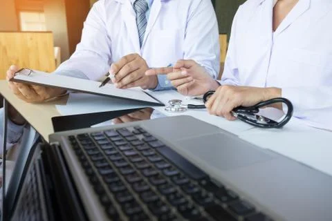 Two doctors discussing patient notes in an office pointing to a clipboard w.. Foto stock