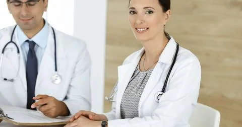 Two doctors discussing treatment problems while sitting at the desk in hospital Stock Photos