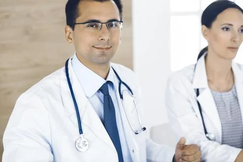 Two doctors discussing treatment problems while sitting at the desk in hospital 스톡 사진