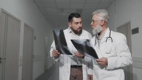 Two doctors engaged in a focused discussion while examining x-ray scans in a Stock Footage 311944610