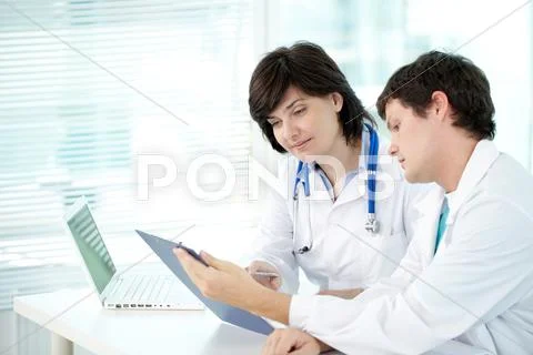 Two doctors examining test result in office Stock Photos