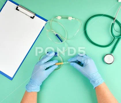 Two doctor's hands in sterile blue gloves holding a drip for Stock Photos