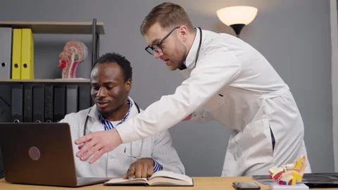 Two doctors in Lab Coats Examining Laptop Screen Stock-Footage 264985912
