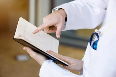 Two doctors looking at diary, mid section, close-up Stock Photos