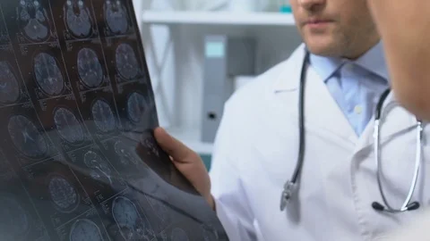 Two doctors looking at x-ray results, discussing patient symptoms and diagnosis Stock-Footage 118905988
