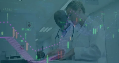 Two doctors at nursing station reviewing health data showing candlestick and Stock Footage 307885189